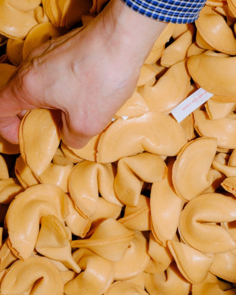 Une main plongeant dans une pile de biscuits de fortune fraîchement produits