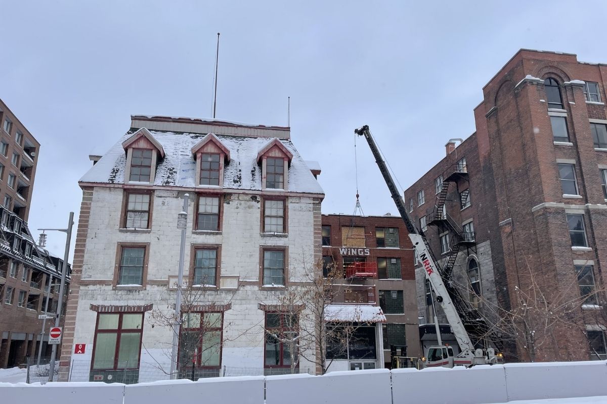A crane moving objects out of the 3rd floor of snow-covered Wing's building